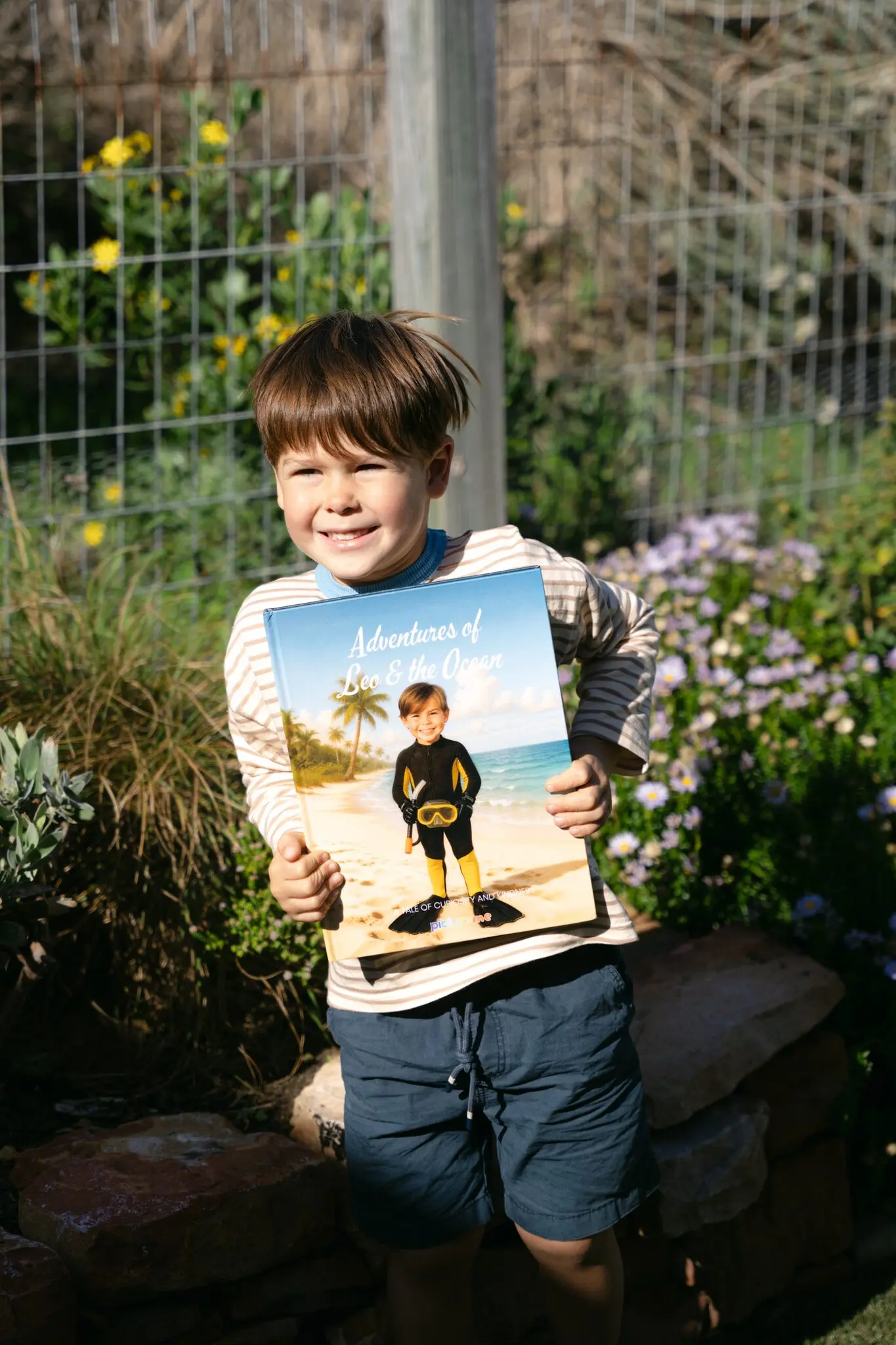 A boy holding his hardcover of Adventures of Leo & the Ocean