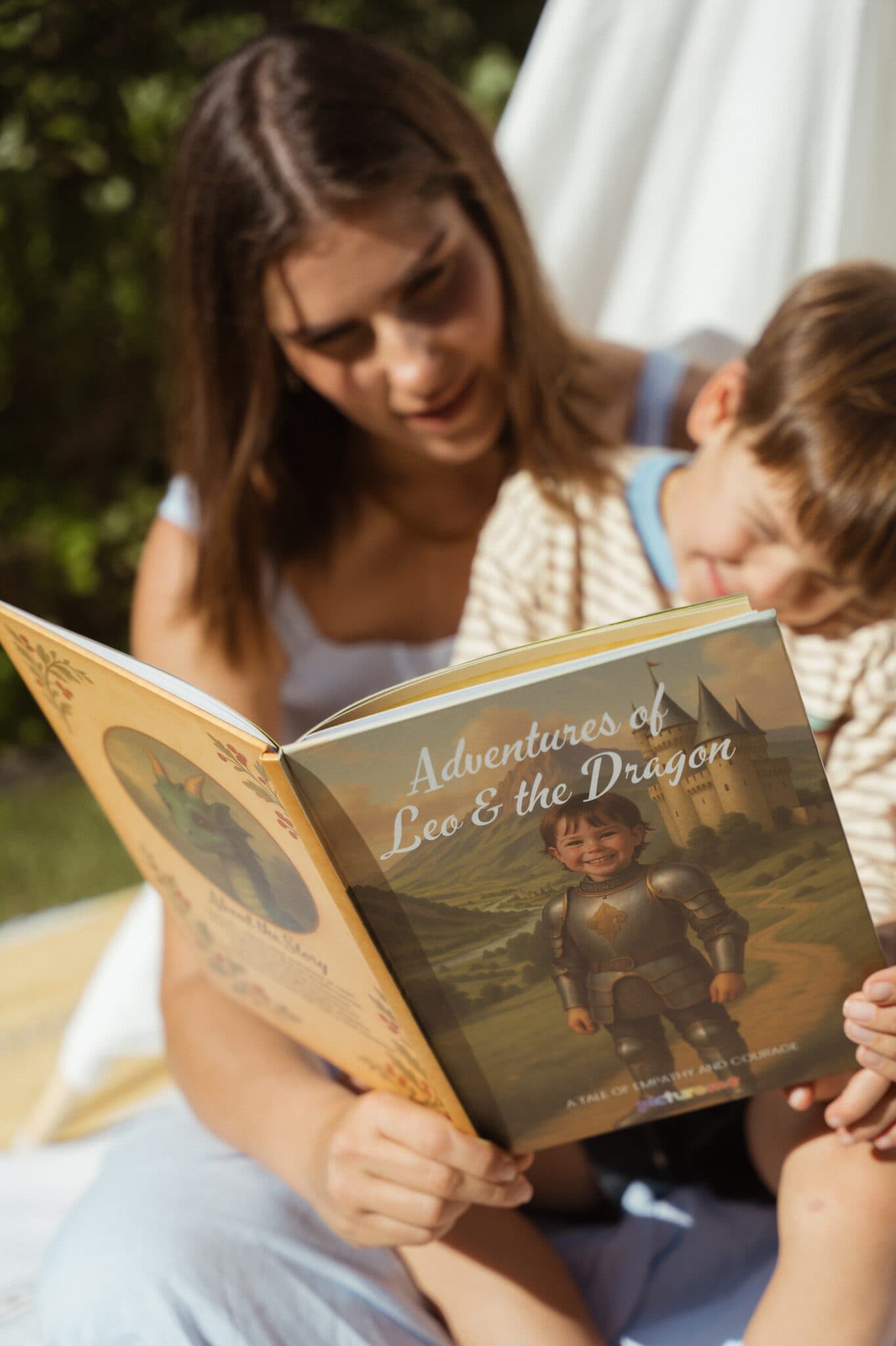 A mom reading the dragon story to her son, the cover facing the camera