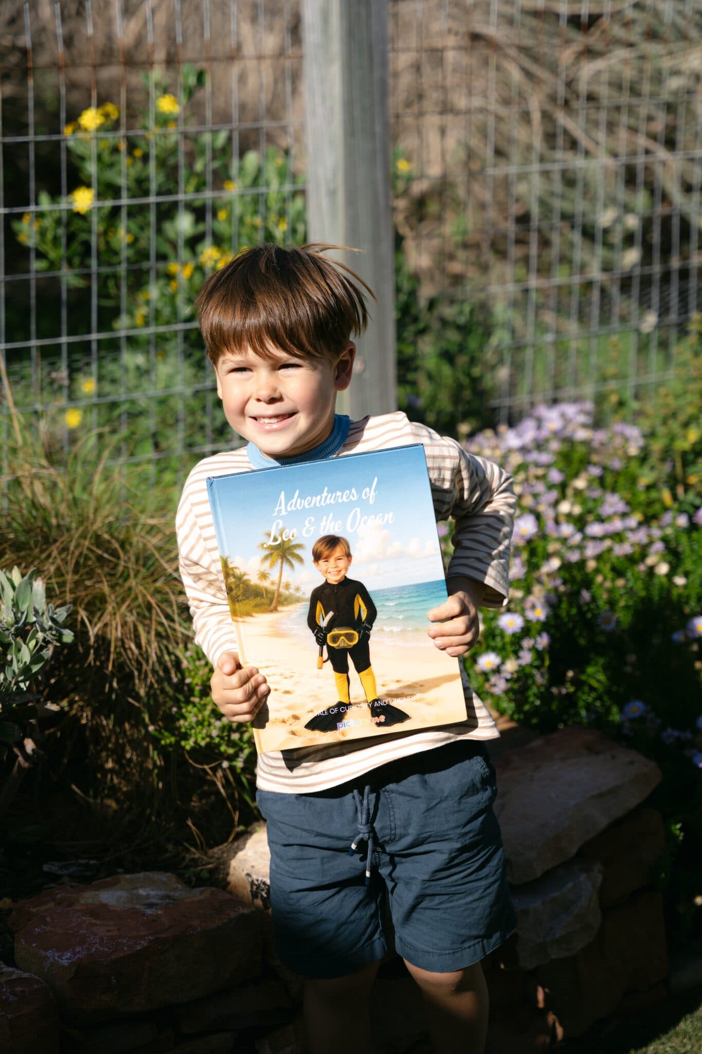 A boy holding his hardcover of Adventures of Leo & the Ocean