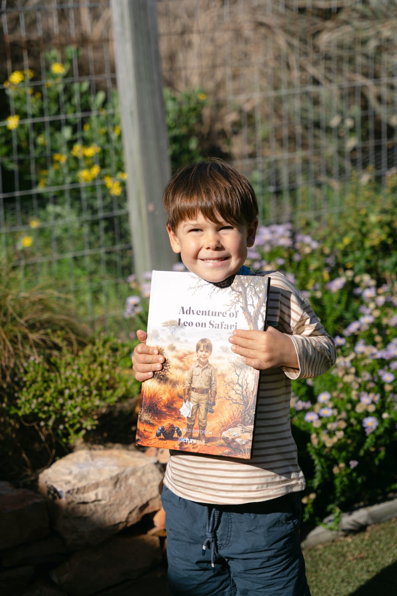 A boy holding his hardcover of Adventure of Leo on Safari