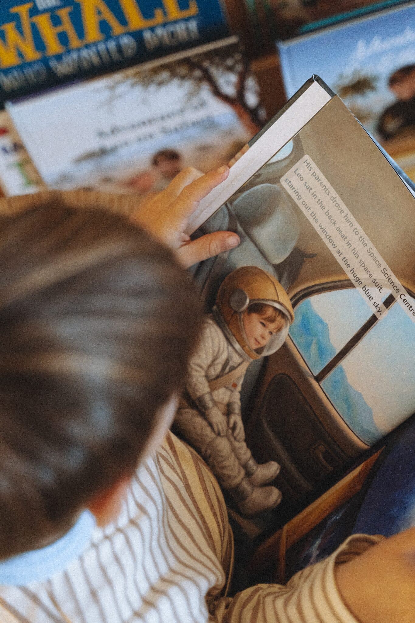 A close-up of an illustrated page inside the space story, a small finger tracing the art