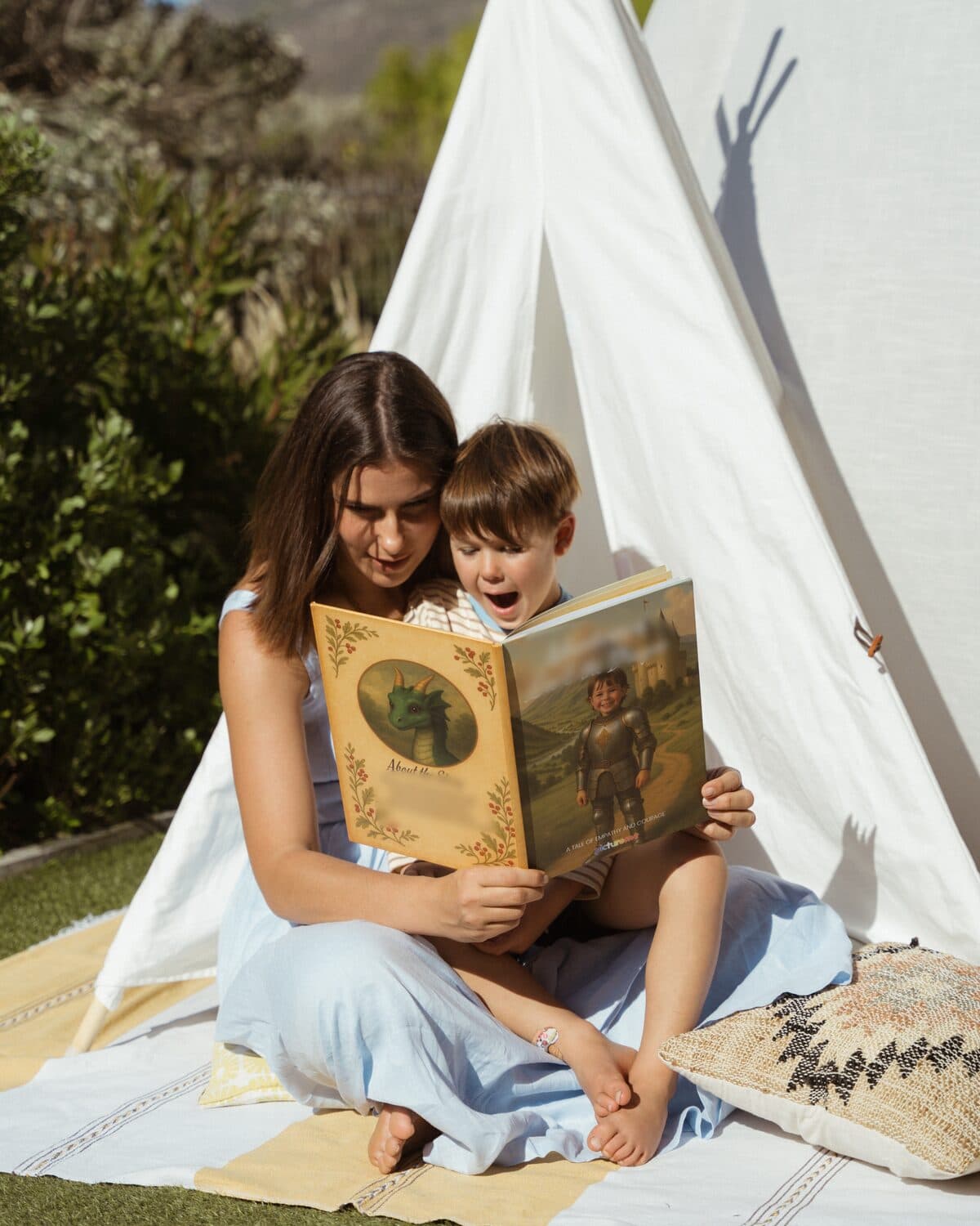 Michaella and her son reading his personalised dragon adventure in a garden teepee