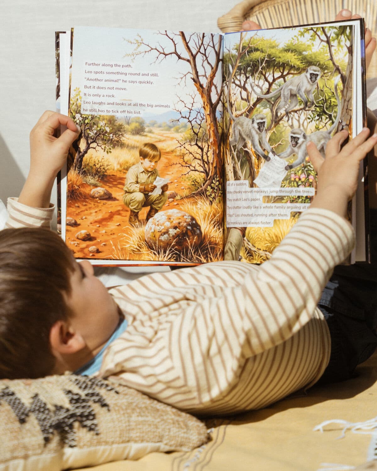 An open spread of the safari book with the boy's illustrated character in the artwork, real boy reading below