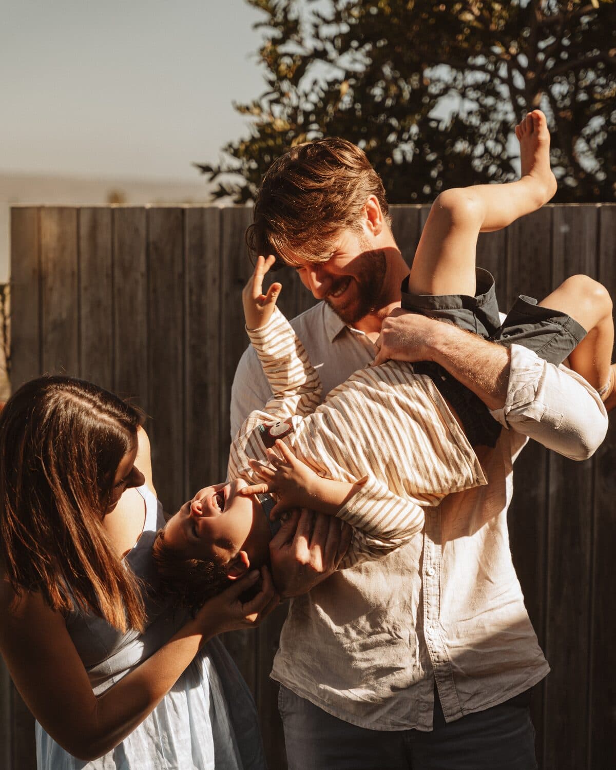Nick lifting their laughing son upside down while Michaella plays along